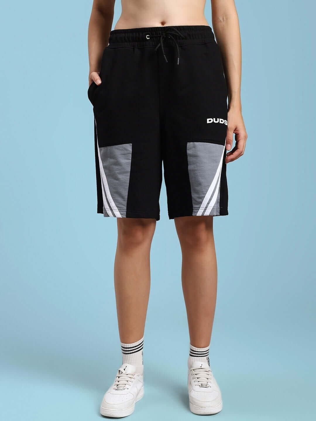 Women's Lewin Chino Regular Fit Shorts in Black-Grey, featuring unique panel design and comfortable fit, paired with white sneakers.