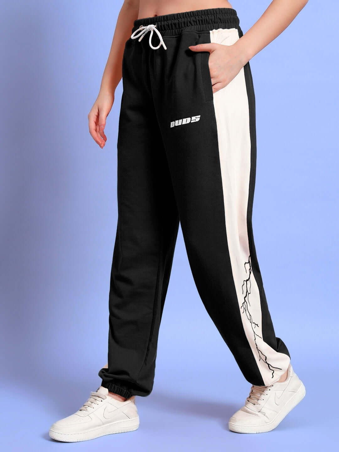 Woman wearing black and white relaxed fit joggers with lightning bolt design, showcasing casual style from DUDS.