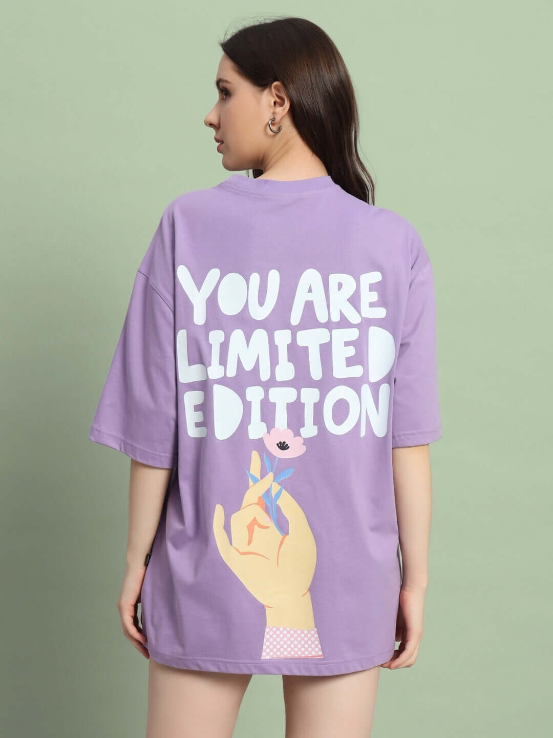 Back view of woman wearing lavender oversized T-shirt with 'You Are Limited Edition' print, showcasing casual style and unique design.