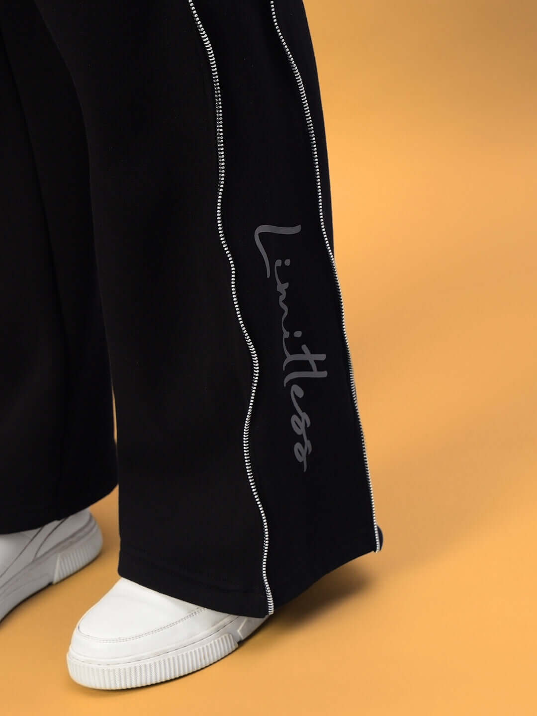 Close-up of black Women's Limitless Fleece Reflector Jogger with white sneakers, highlighting elegant reflective detailing and custom fit option.