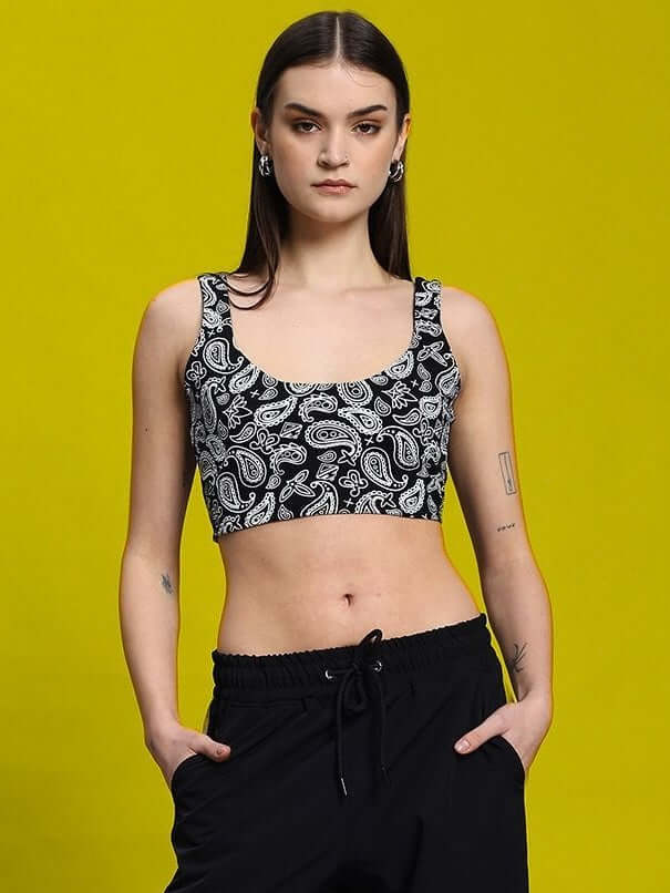 Woman wearing a black paisley print crop-top with drawstring pants against a bright yellow background.