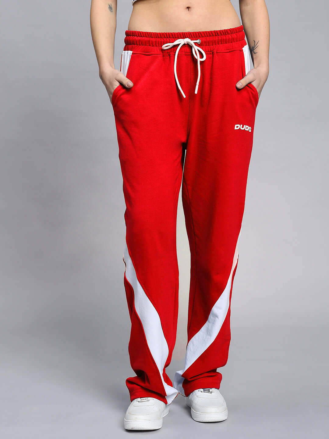 Model wearing WOMEN'S LIVIANA COOL CO-ORD SET RED featuring red sweatpants with white stripes from WEAR DUDS, capturing modern street-chic fashion.