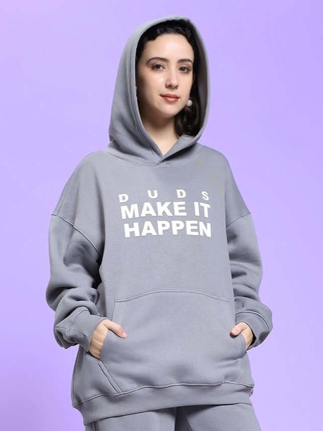 WOMEN'S MAKE IT HAPPEN FLEECE HOODIE GREY on woman with hands in pockets, showcasing comfortable and stylish design.