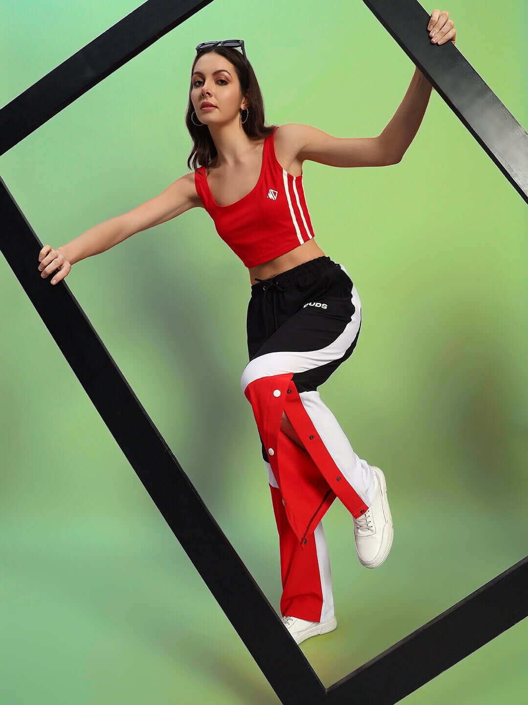 Woman wearing women's Marco relaxed fit cargo pants in black and red, posing against a geometric frame with a vibrant background.