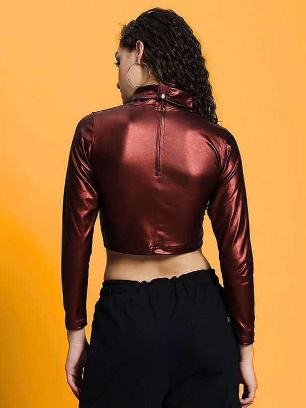 Back view of a maroon metallic women's crop top showcasing the sleek design and texture, styled with black pants, on a bright background.