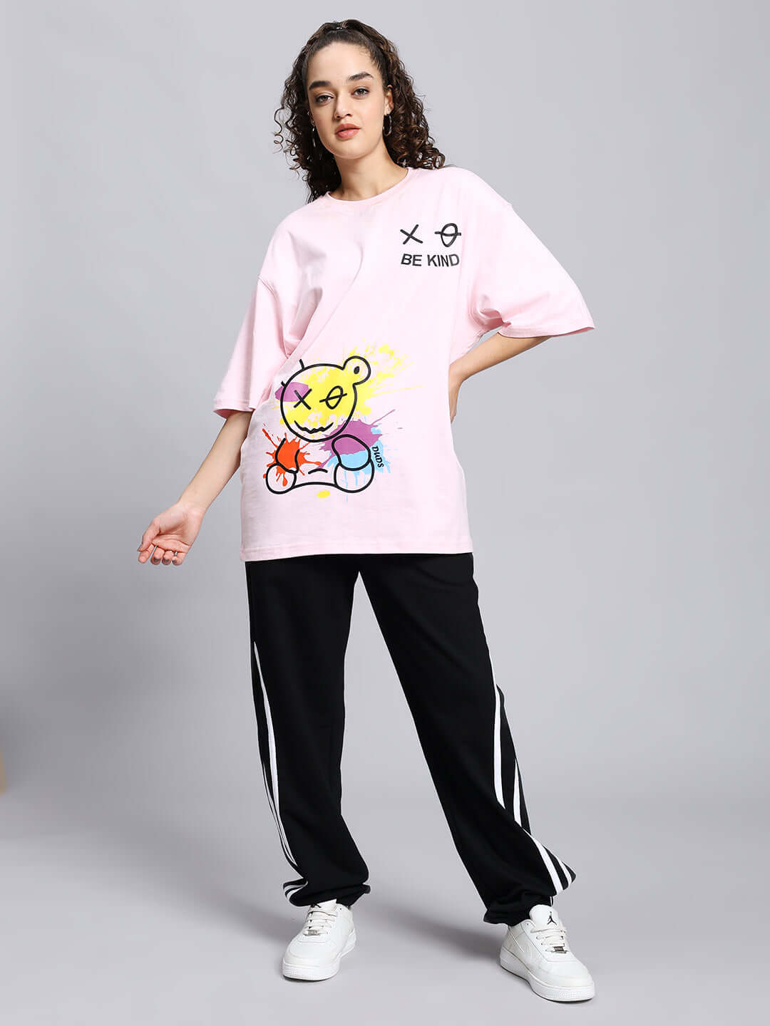 Model wearing Women's Megastar 2 Stripe Jogger in Black with casual pink graphic tee and white sneakers, posing fashionably.