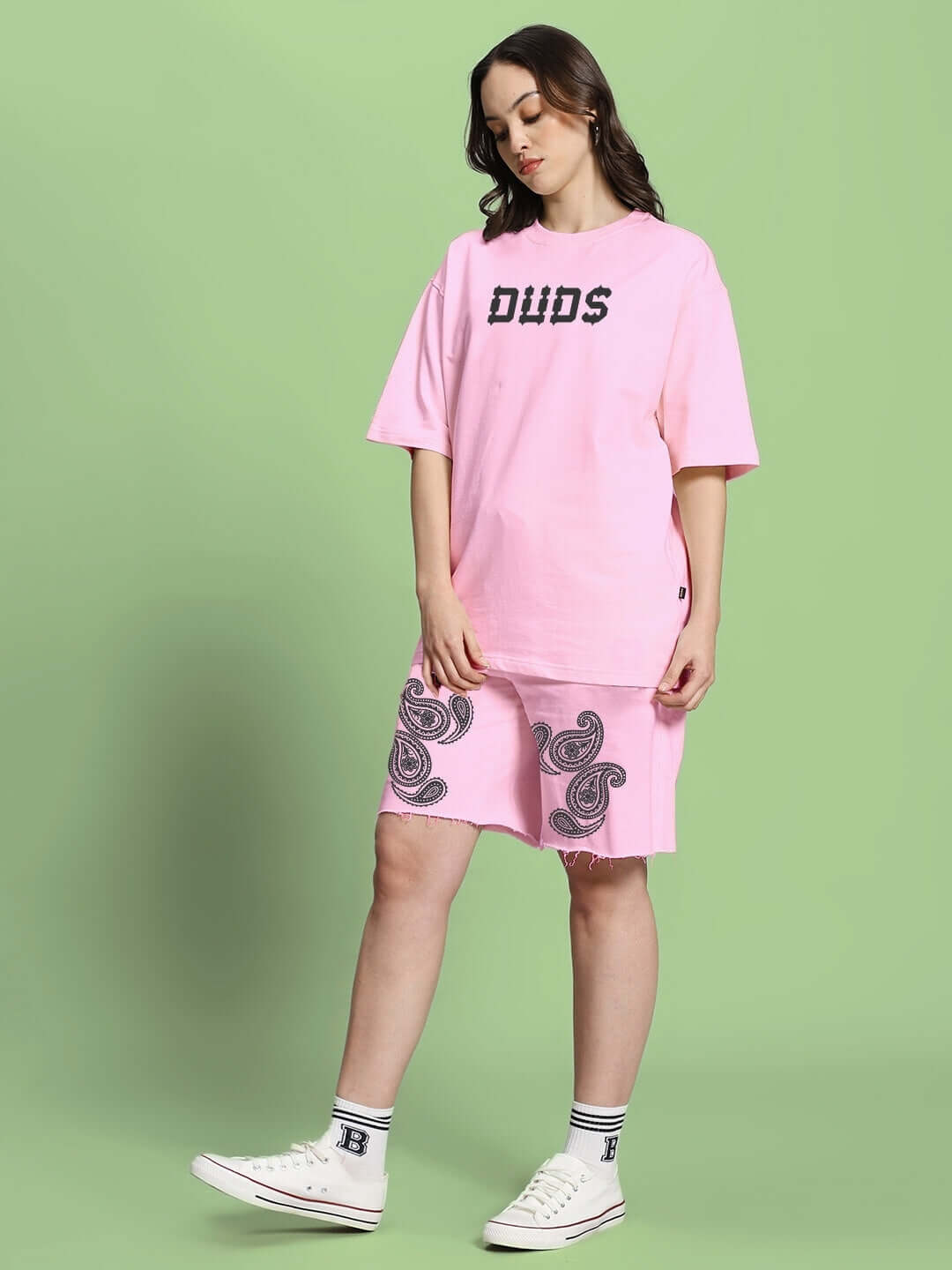 Woman wearing WOMEN'S MESSI PAISLEY PRINT CO-ORD SET PINK with paisley design against green background.