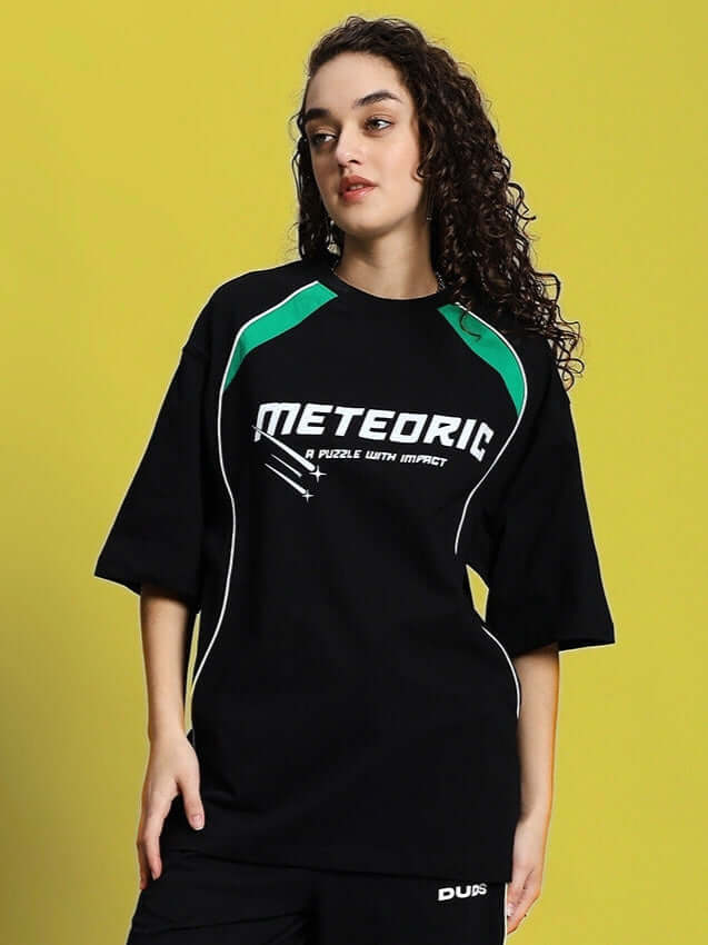 Woman wearing black meteoric oversized t-shirt made of premium cotton with green accents, ideal for casual wear. Made in India.