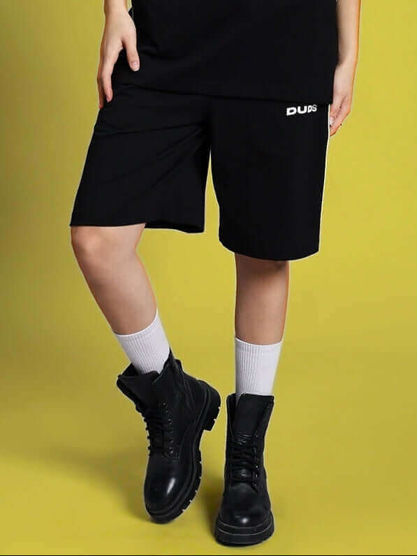 Women's Meteoric Regular Fit Shorts in Black with customizable size options, paired with black boots and white socks on a yellow background.