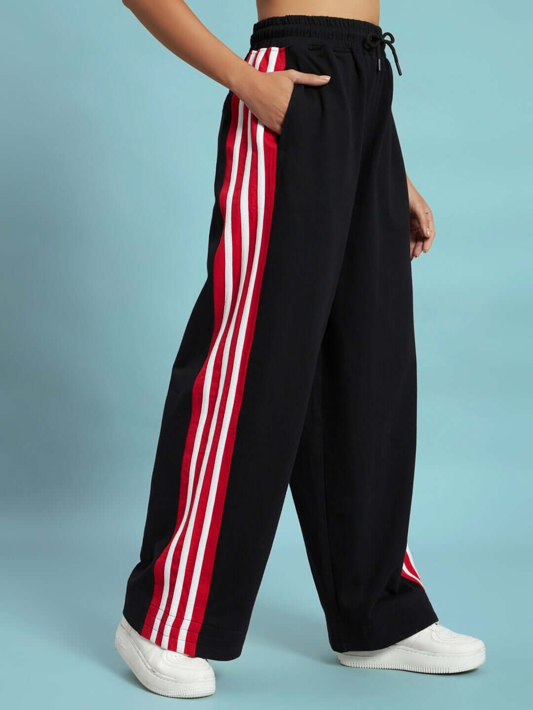 WOMEN'S MILANO RELAXED-FIT JOGGERS BLACK-RED Woman wearing black-red Milano relaxed-fit joggers with side stripes, showcasing casual style and comfort, made by DUDS with custom fit available.