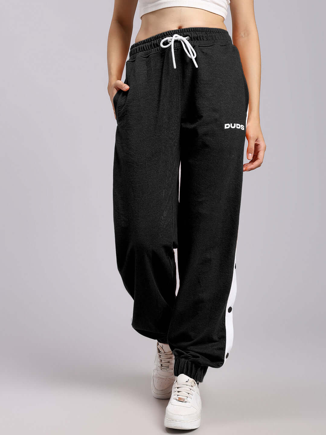Alt Tag: Woman wearing black relaxed fit joggers by DUDS, featuring drawstring waist and side stripe. Made to order jogger pants.