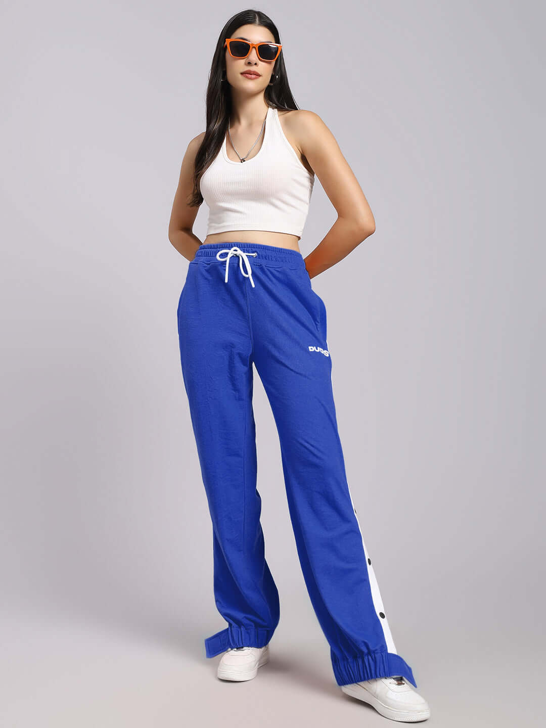 Woman wearing Women's Miller Relaxed Fit Joggers in blue, paired with a white top and sunglasses, showcasing comfortable style.