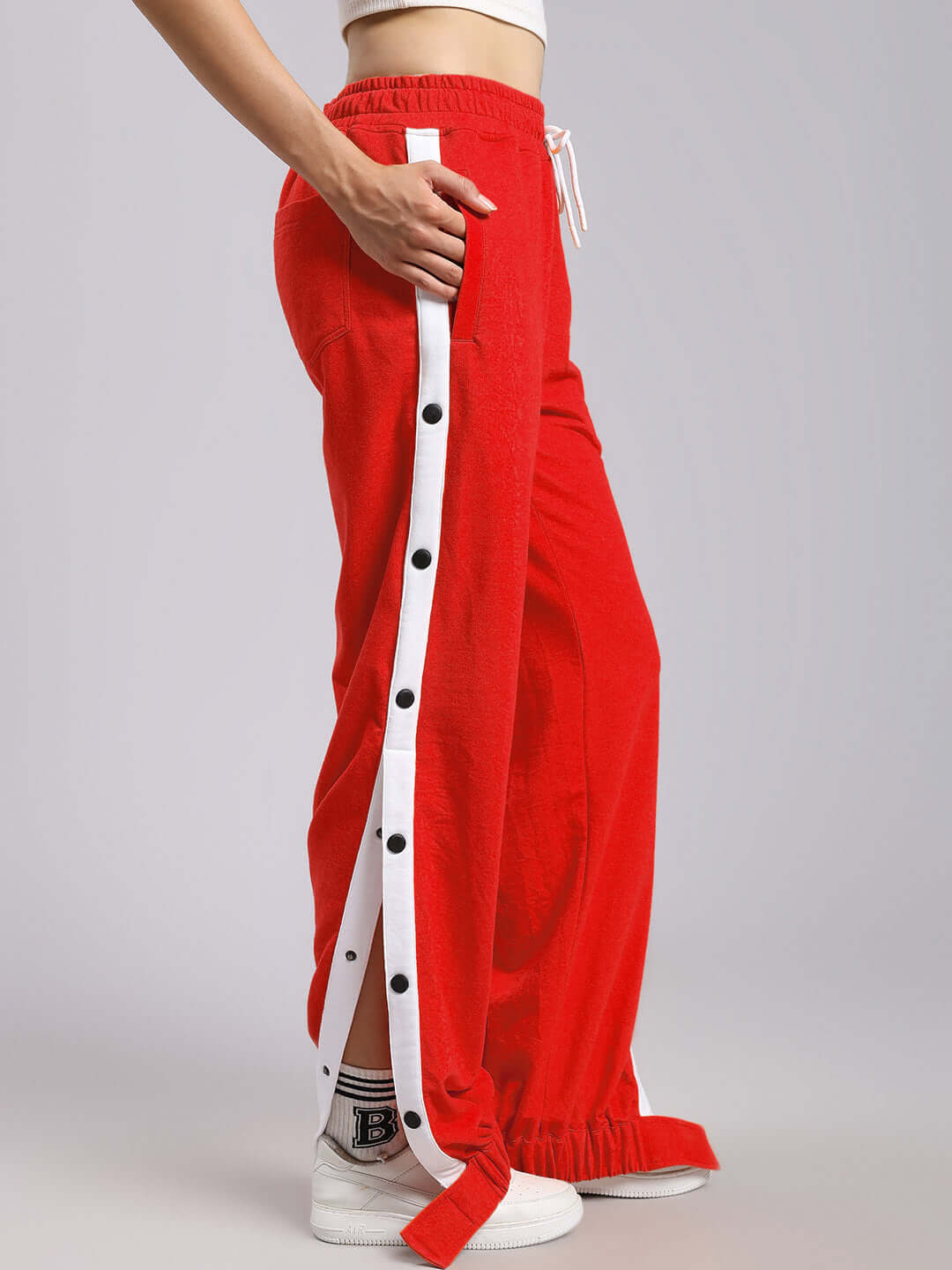 Woman wearing red relaxed fit joggers with white side buttons, showcasing casual fashion style.