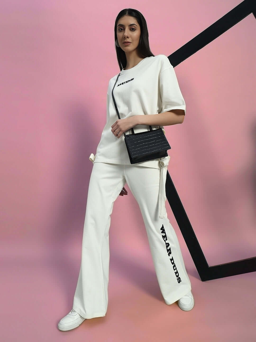 Model wearing Women's Moon Night Co-Ord Set in off-white with relaxed fit joggers, elasticated waistband, styled with a black bag.