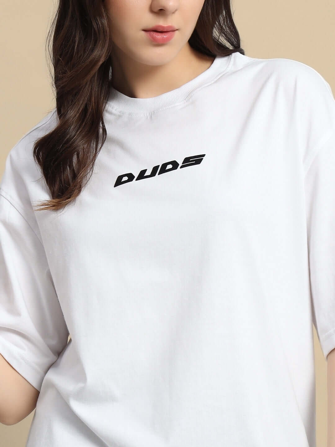 Woman wearing oversized white t-shirt with black text, featuring premium cotton blend fabric. Designed in India.