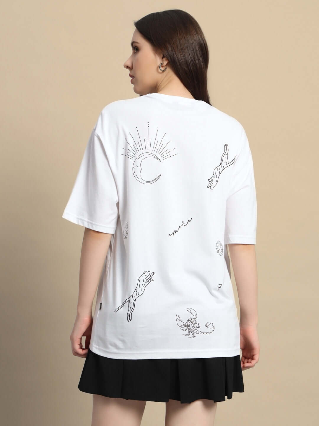 Back view of a women's oversized white t-shirt with celestial and animal designs, made from premium cotton, styled with a black skirt.