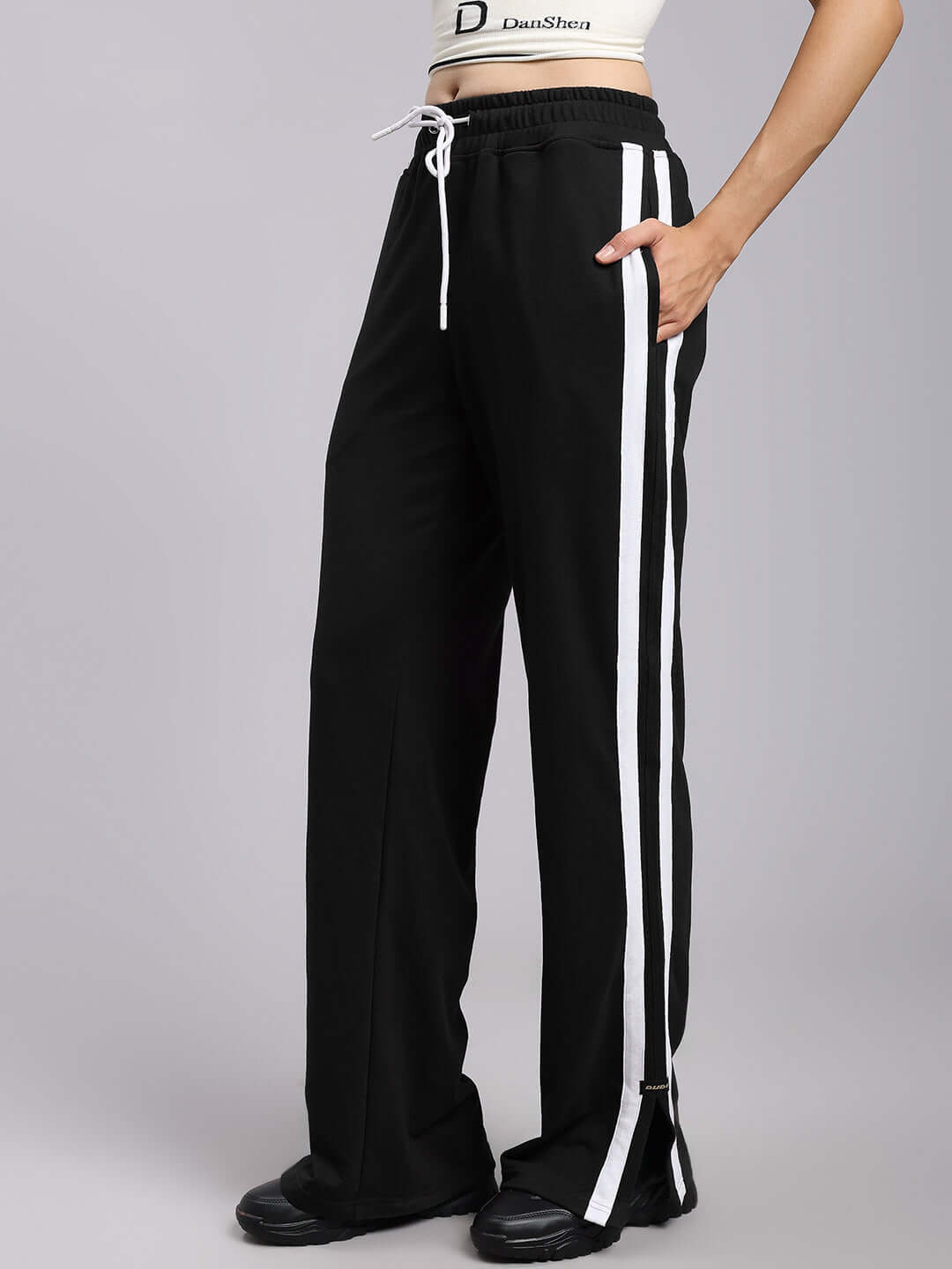 Woman wearing black relaxed fit joggers with white side stripes, highlighting comfortable and stylish design for women.
