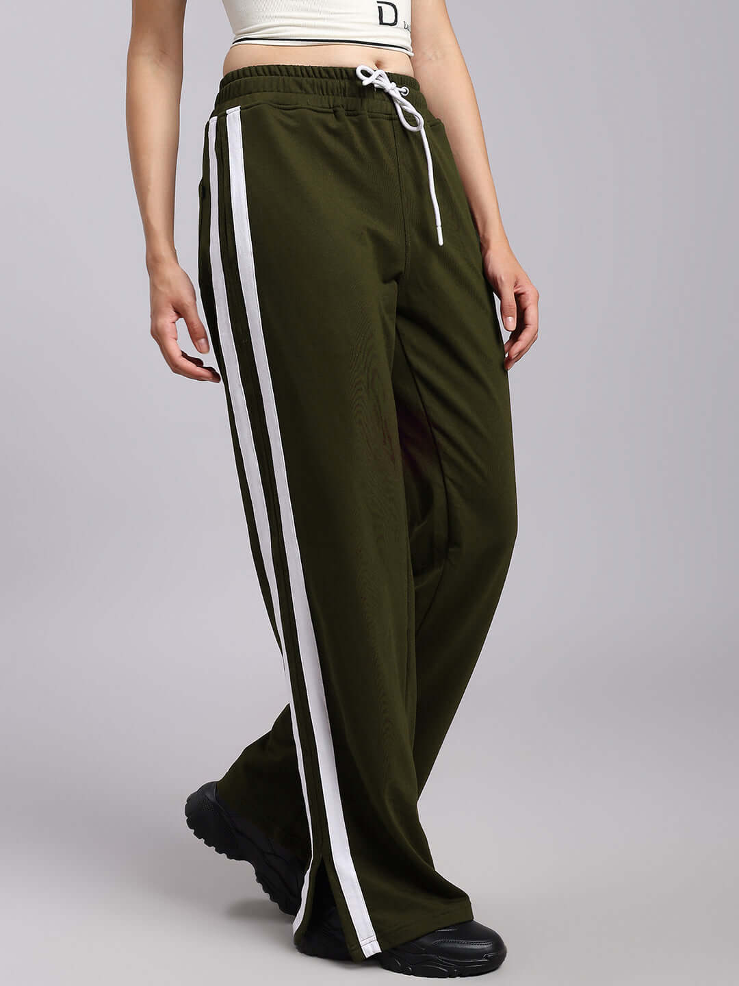 Woman wearing olive green relaxed fit joggers with white stripes, made by DUDS, available for custom sizing.
