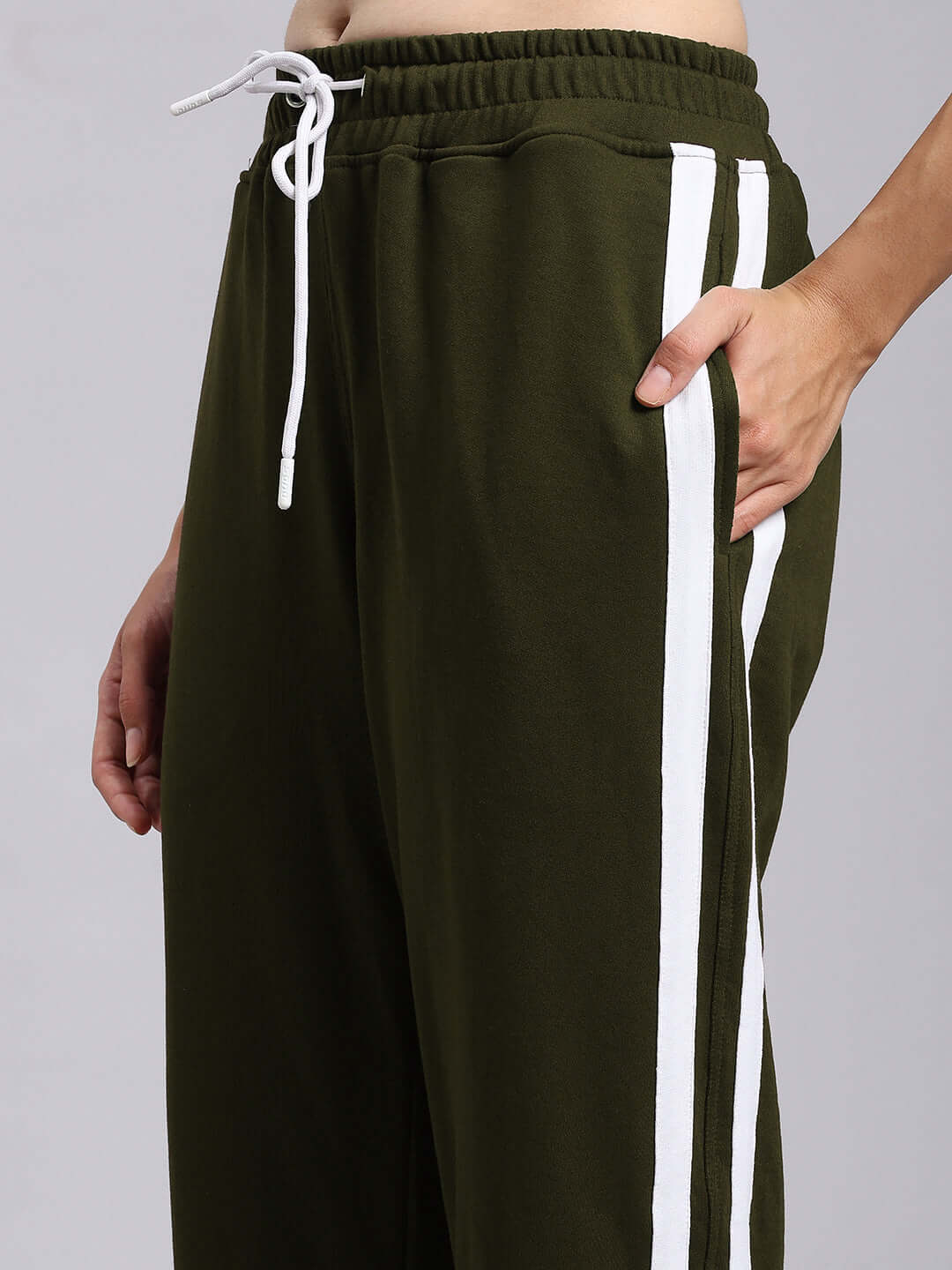 Woman wearing olive green relaxed fit joggers with white stripes and drawstring waistband.