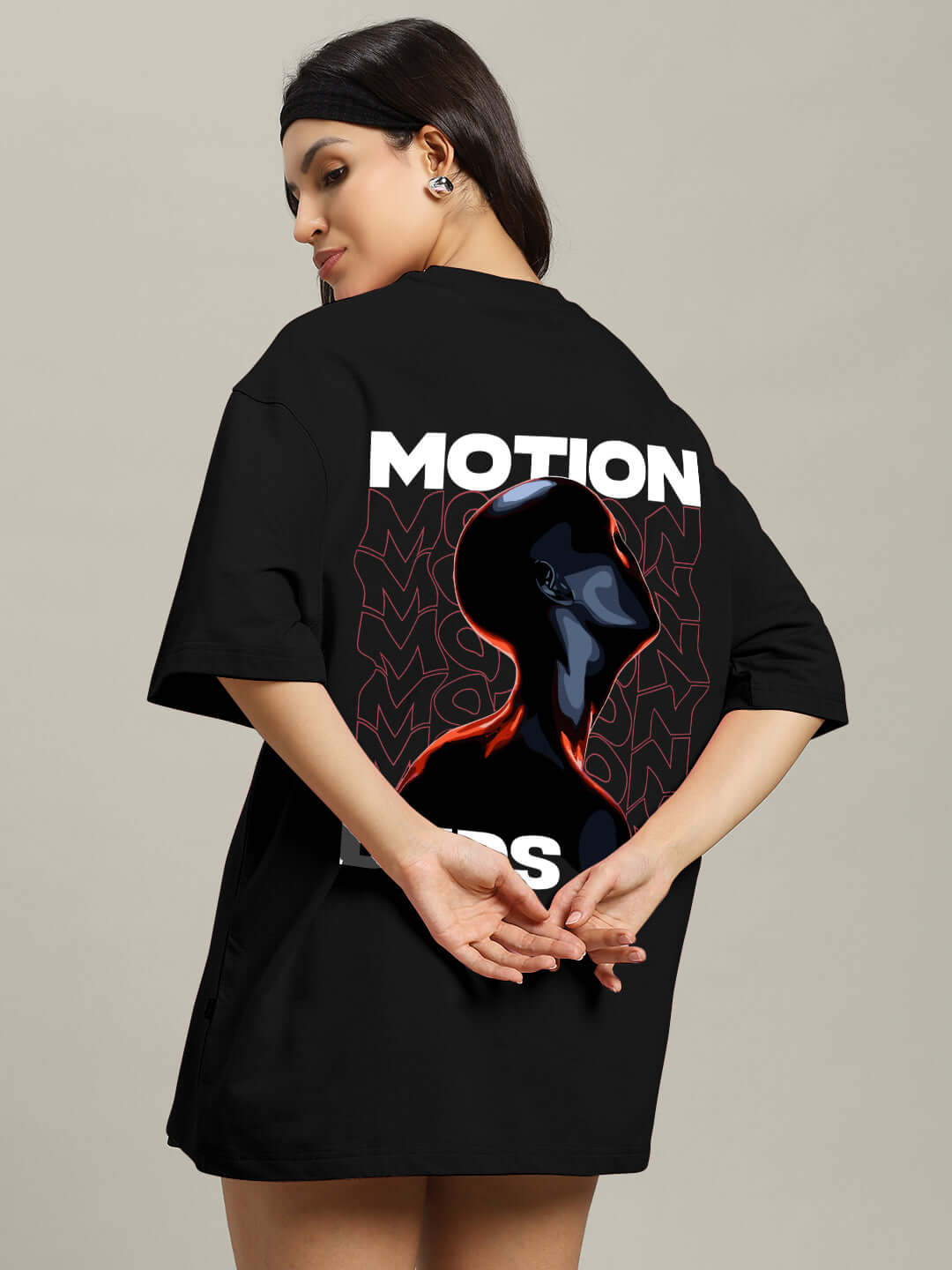 Woman wearing oversized black t-shirt with "Motion" graphic, made from premium cotton and elastane. Perfect for stylish comfort.