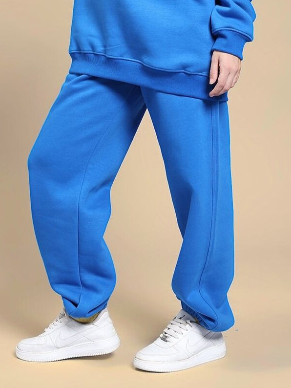 Person wearing WOMEN'S NATURE LINK FLEECE JOGGER ROYAL BLUE with white sneakers on a beige background.