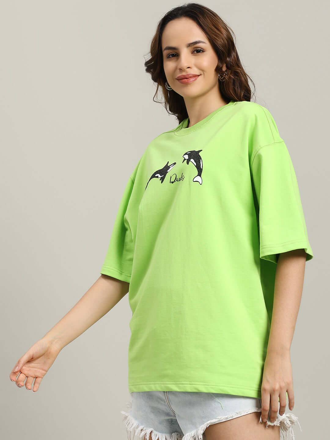 Woman wearing WOMEN'S ORCAS OVER-SIZED T-SHIRT NEON GREEN with orca graphics.