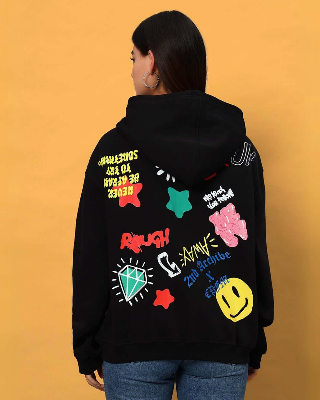 Back view of WOMEN NEVER BE AFRAID FLEECE HOODIE BLACK with colorful graphics, worn by a woman.