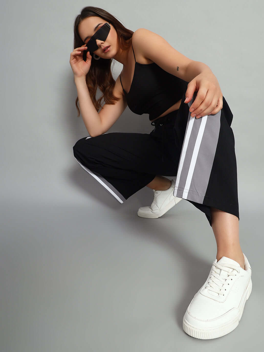 Woman wearing black Nitro Relaxed Fit Cargo Pants with white stripes, styled with a black top and white sneakers.
