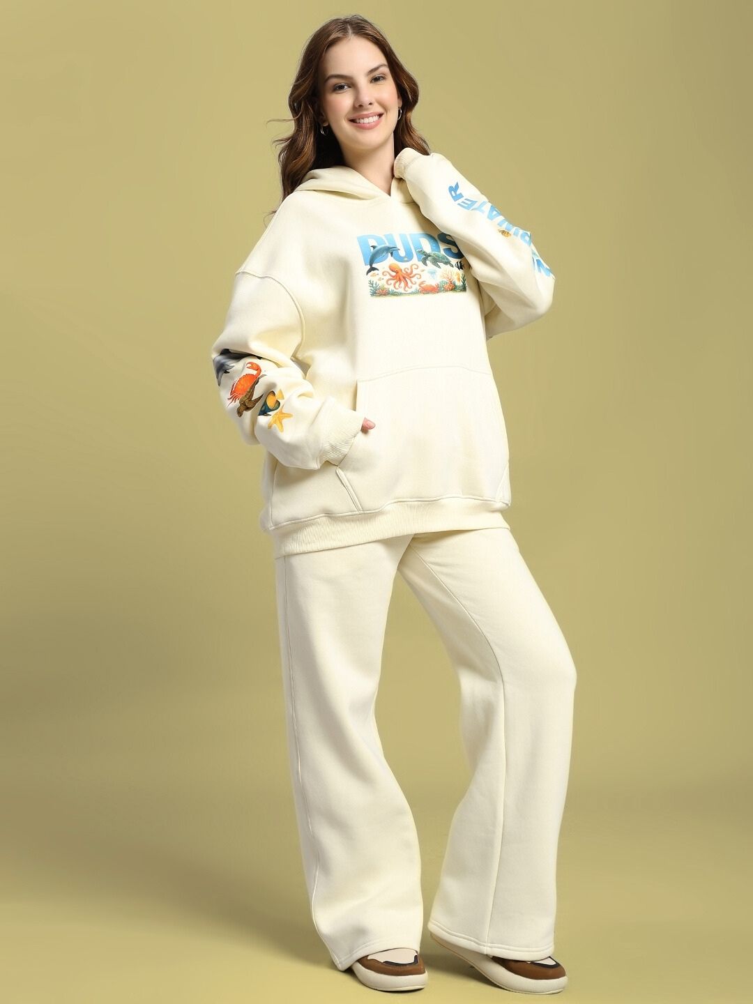 Woman wearing WOMEN'S OCEAN BUDDIES FLEECE CO-ORD SET OFF-WHITE with sea-inspired graphics, displaying comfort and style.