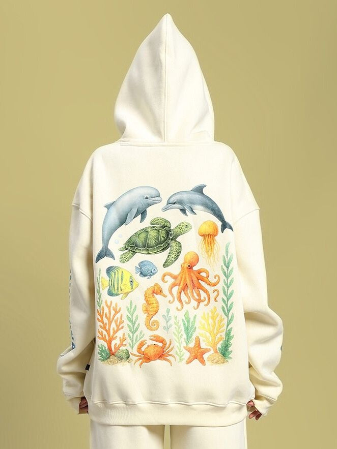 Model wearing WOMEN'S OCEAN BUDDIES OVERSIZED FLEECE HOODIE OFF-WHITE with aquatic design on back