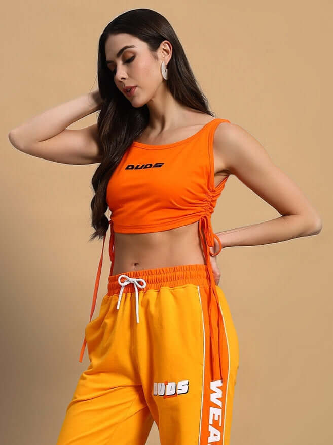 Woman wearing orange crop-top and matching joggers, featuring premium heavy gauge 100% cotton fabric. Ideal for casual wear.