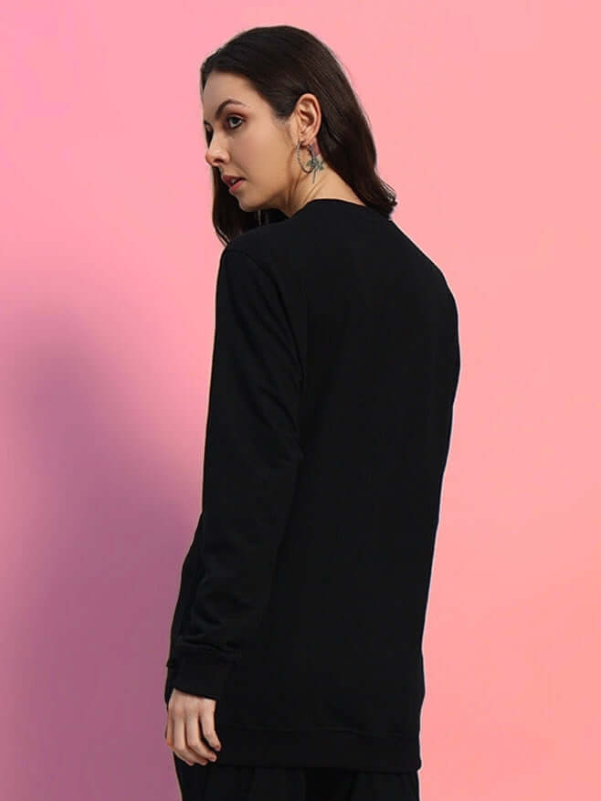 Back view of WOMEN'S OUTLOOK SWEATSHIRT BLACK WITH WHITE STRIPE worn by model against a pink background.