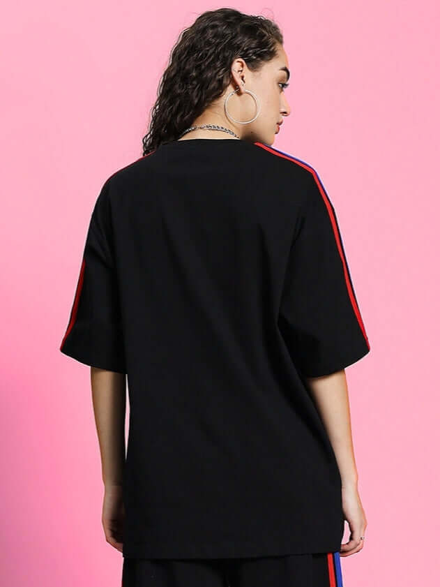 Back view of woman's oversized black T-shirt with rainbow stripes on sleeves, made from premium heavy gauge cotton for stylish comfort.