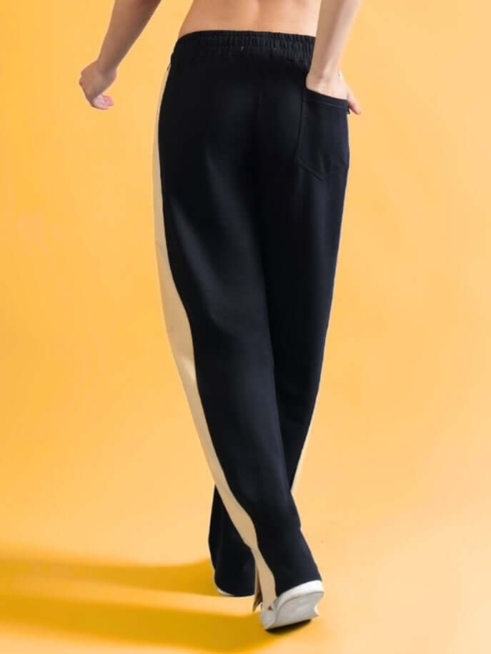 Model wearing Women's Paradise Side Slit Joggers in Black-Beige against a yellow background, showcasing the stylish side slit design.