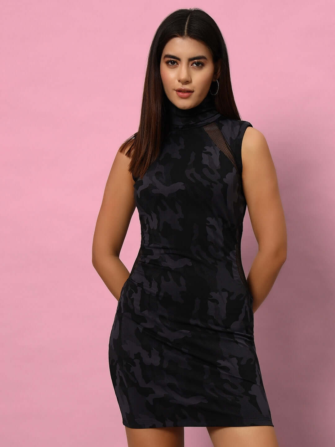 Woman wearing a camo blue passion dress with reflector piping, made of 90% polyester and 10% spandex, against a pink background.