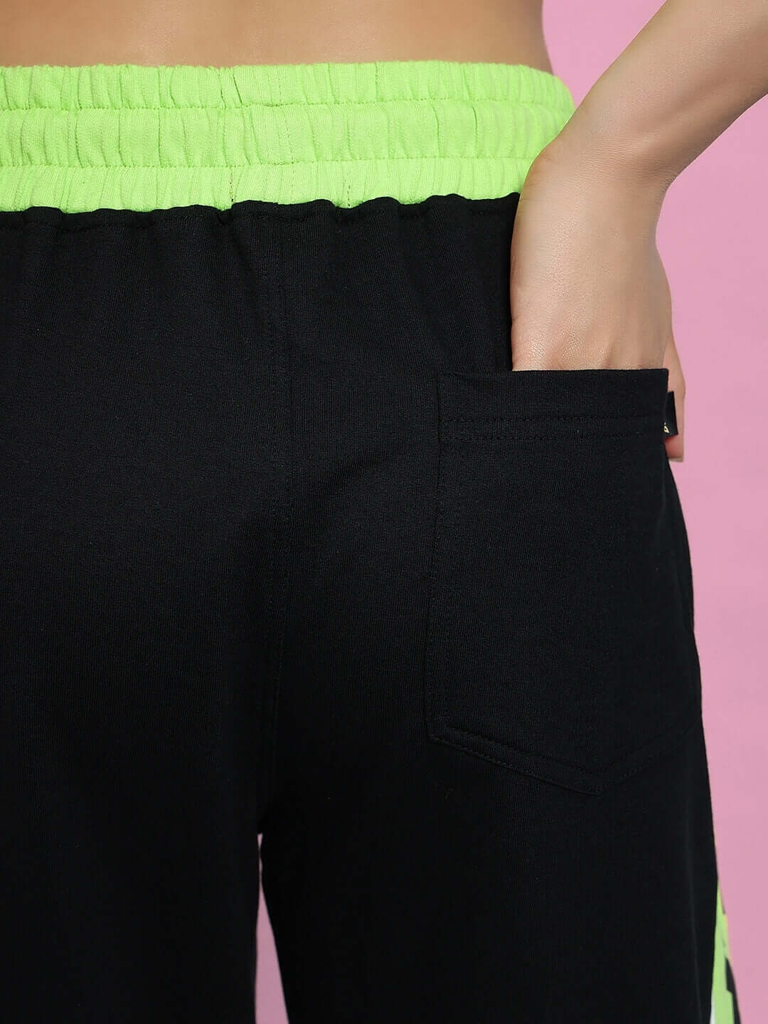 Close-up of women's black joggers with neon green waistband, featuring a pocket detail. Fashionable and customizable fit from DUDS.