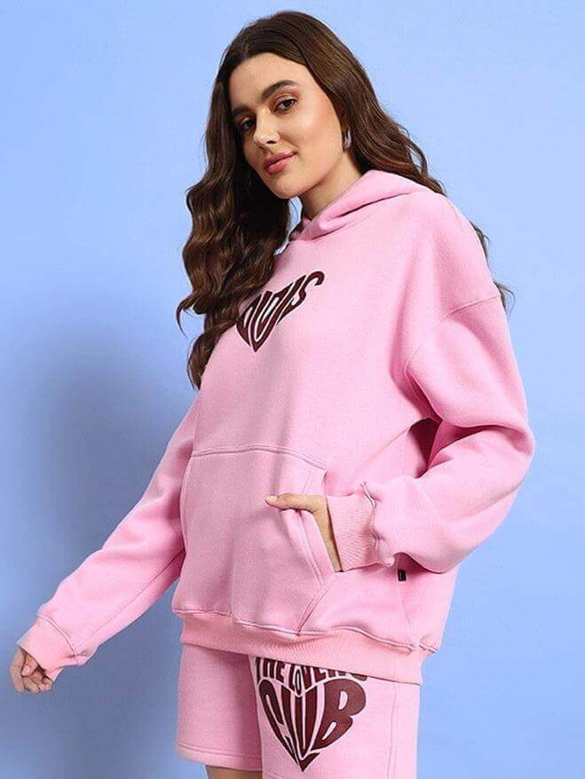 Woman wearing WOMEN LOVERS CLUB FLEECE HOODIE PINK with stylish design, showcasing modern comfort and elegance.