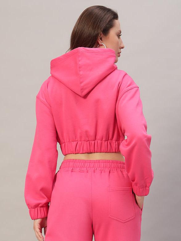 Back view of a woman wearing a pink oversized crop hoodie made of heavy gauge cotton fleece. Ideal for casual wear.