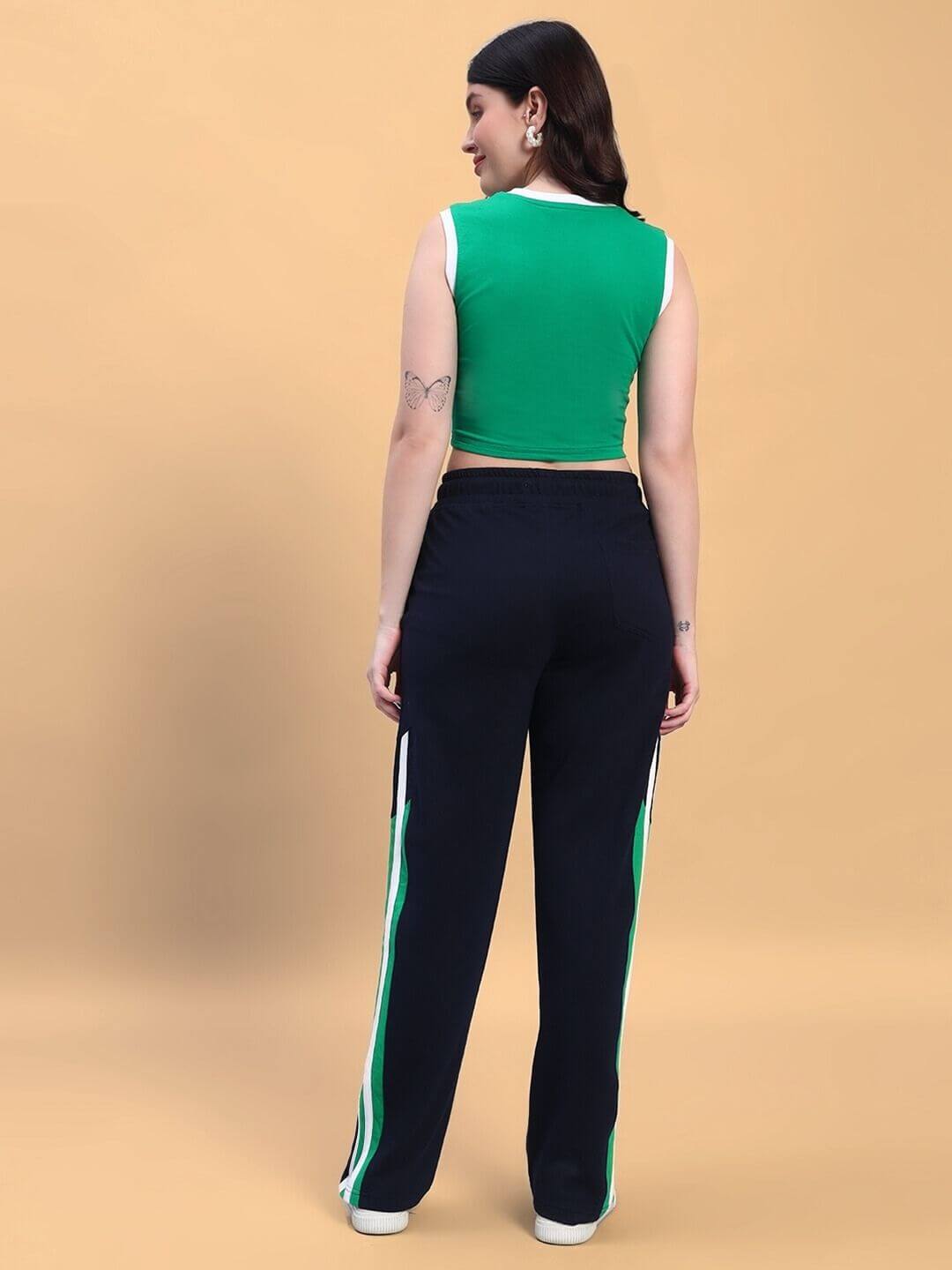 Back view of woman wearing WOMEN'S PLAYER CO-ORD SET GREEN NAVY, showcasing sporty design with green top and navy pants with stripe detail.