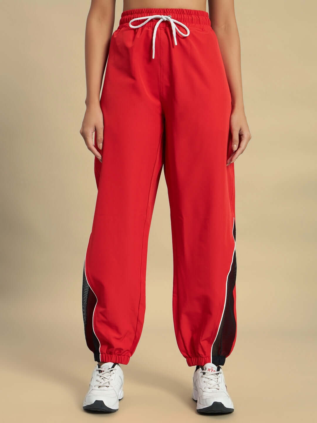 Woman wearing red Women's Plexus Joggers by DUDS, featuring a drawstring waist and stylish side stripes for a comfortable fit.