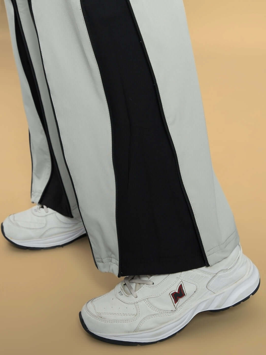 Close-up of women's grey parachute cargo pants with black accents, showcasing unique style and custom fit option. Paired with white sneakers.