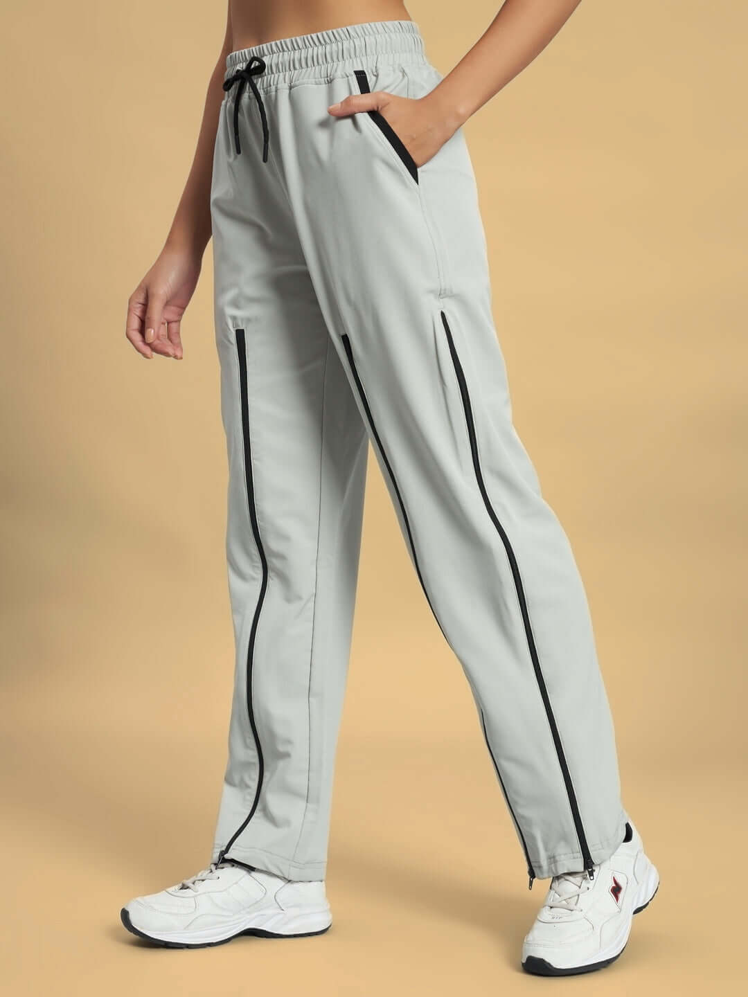 Women's grey parachute cargo pants with black trim, elastic waistband, and white sneakers.