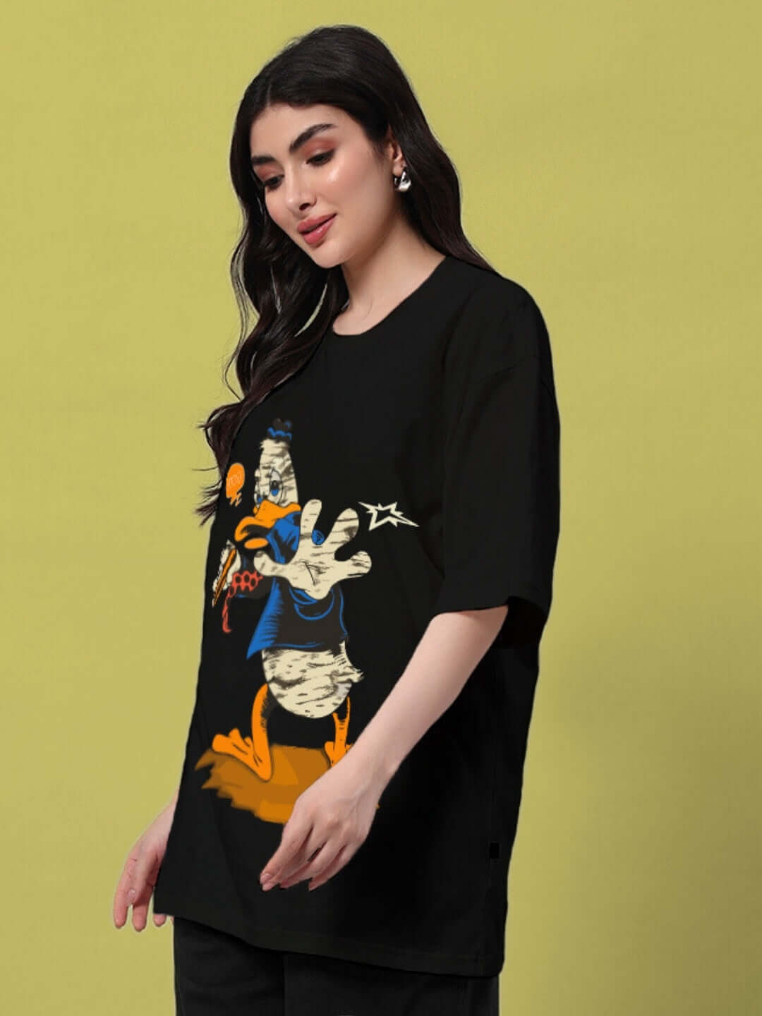 Woman wearing oversized black t-shirt with cartoon graphic, ideal for casual summer style, pairing effortlessly with shorts, skirts, or jeans.