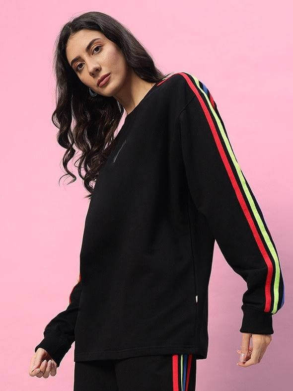 Black women's rainbow oversized co-ord set with colorful stripe design, featuring a relaxed fit and elastic waistband, against a pink background.