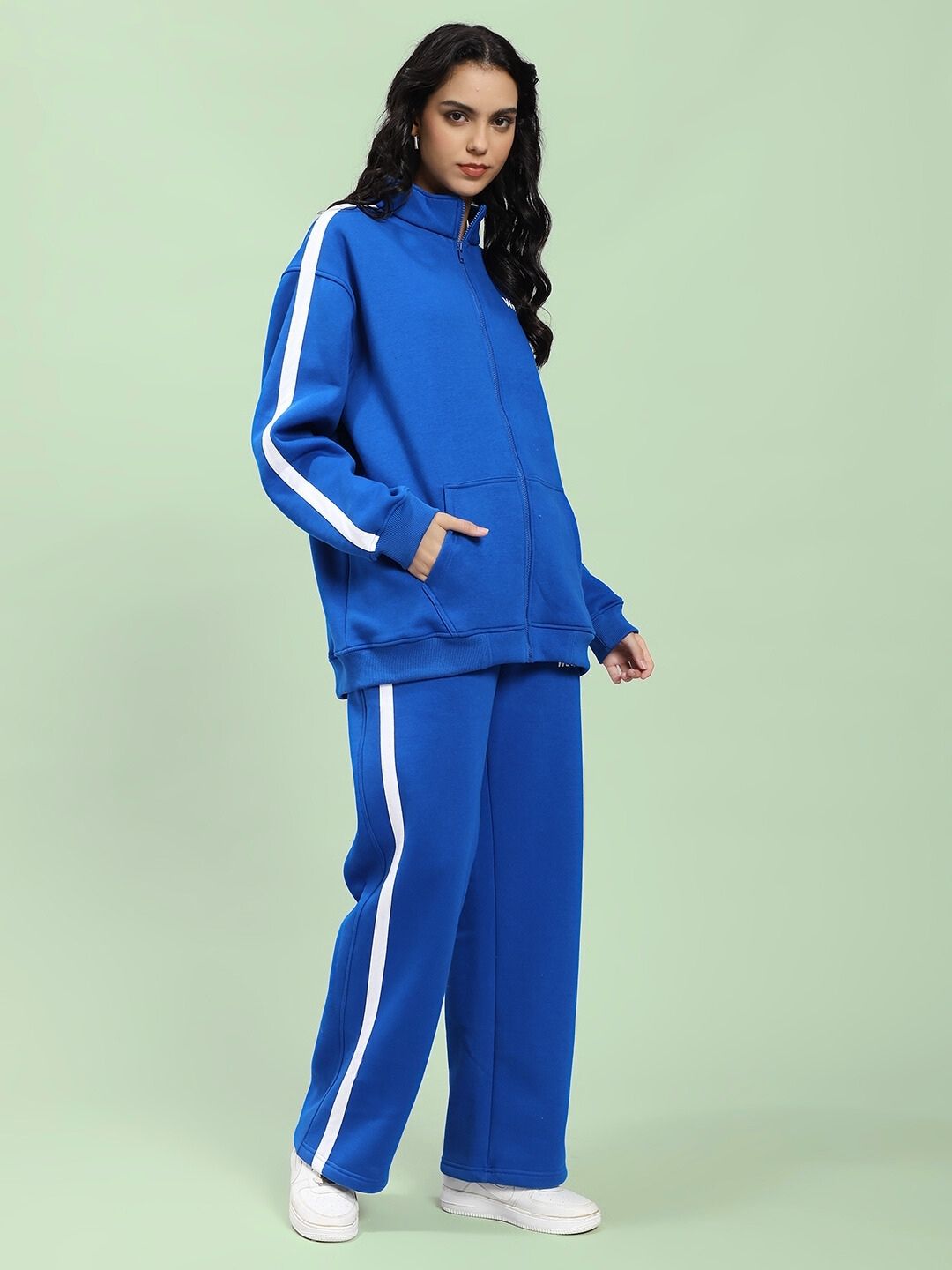 Woman wearing WOMEN RAPID STRIDE ROYAL BLUE COTTON FLEECE CO-ORD SET standing against green background.