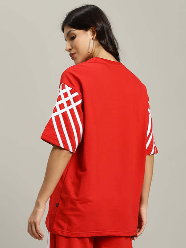 Model wearing women's United Stripe oversized red t-shirt made from premium cotton fabric, featuring white striped sleeves, back view.