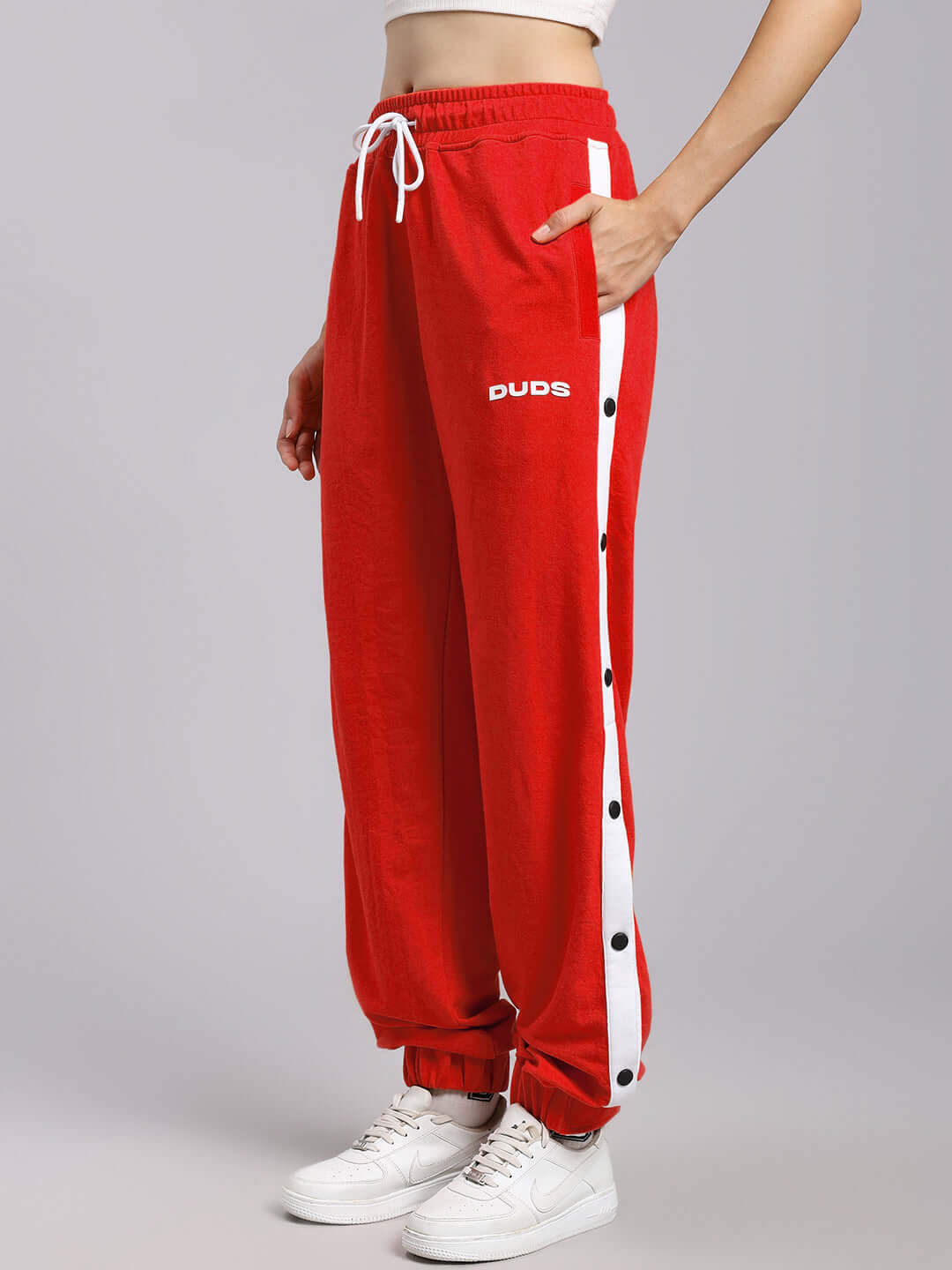 Women's red joggers by DUDS with white side stripe and buttons, relaxed fit style, worn with white sneakers. Made to order.