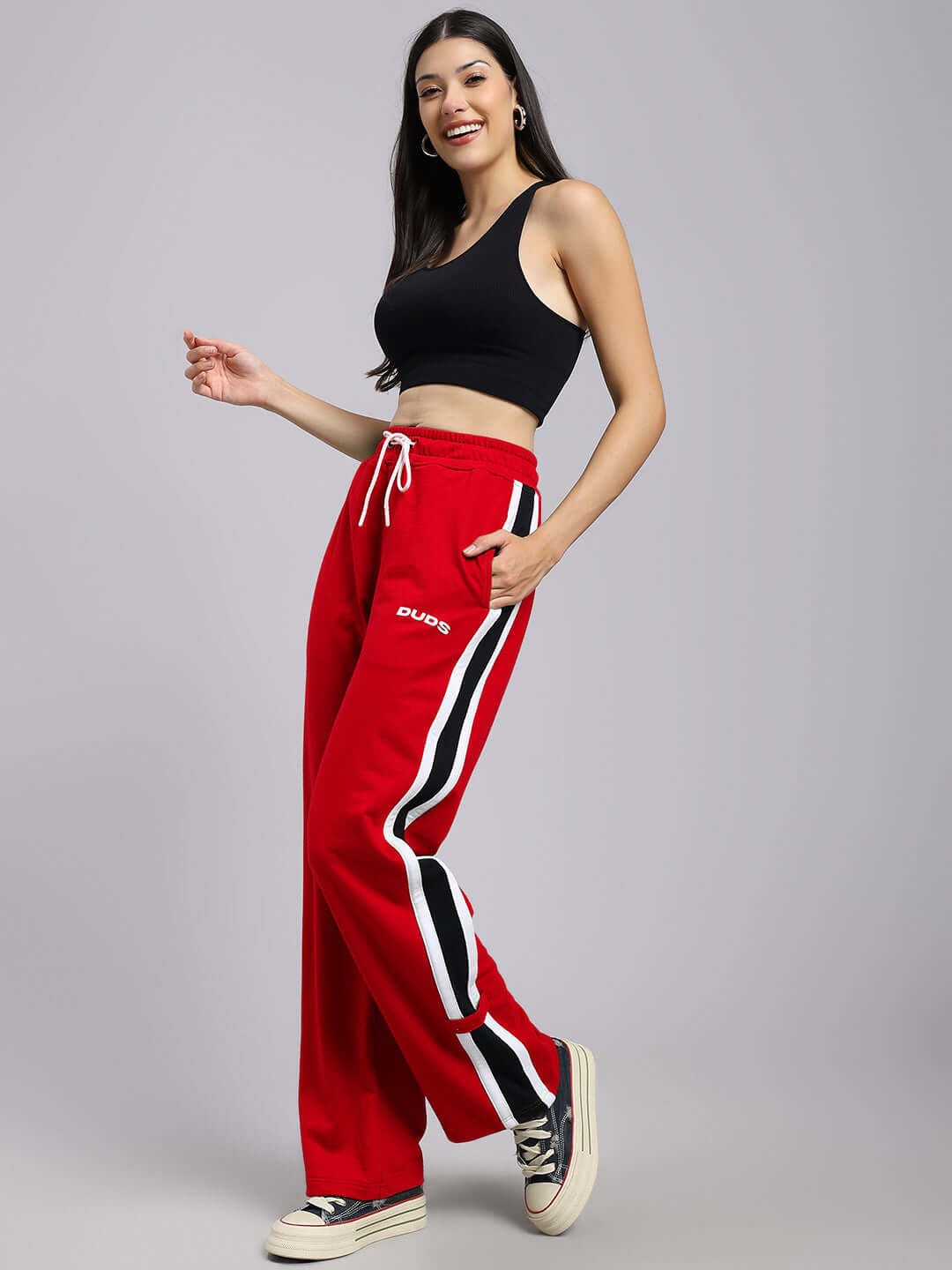 Model wearing red Women's Rosston Flat-Out Relaxed Fit Joggers from DUDS with side stripes.