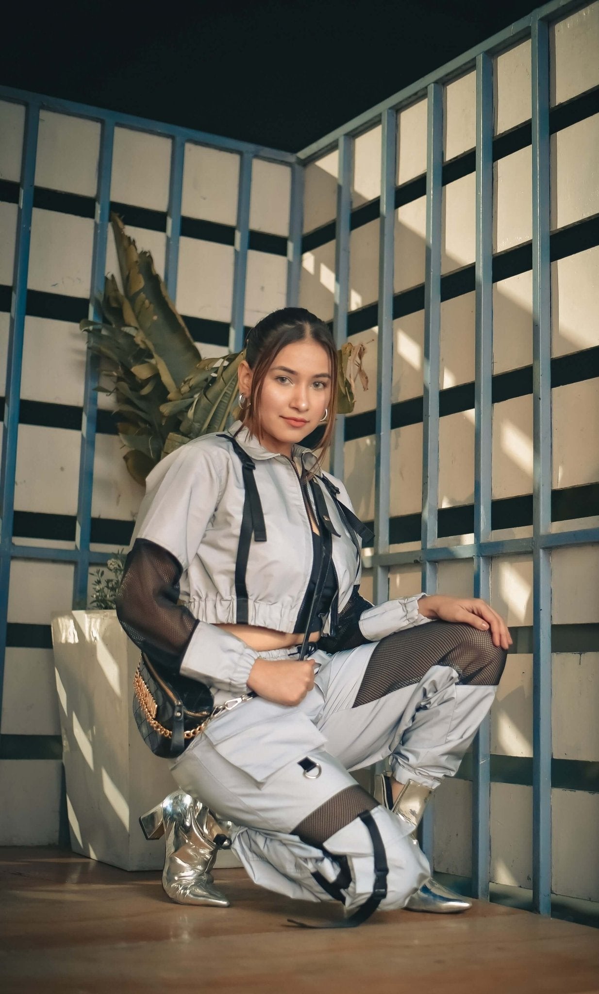 Model wearing WOMEN REFLECTOR CO-ORD SET CARGO PANTS WITH JACKET, showcasing reflective fabric and streetwear style in a modern setting.