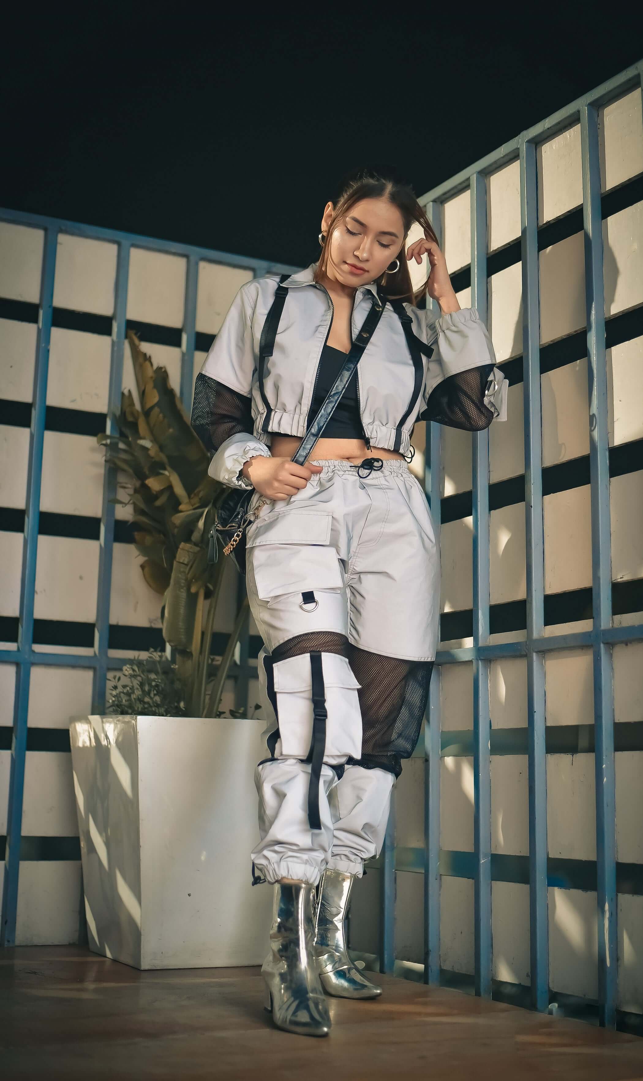 Fashionable woman wearing DUDS women's reflector co-ord set with cargo pants and jacket, standing stylishly.